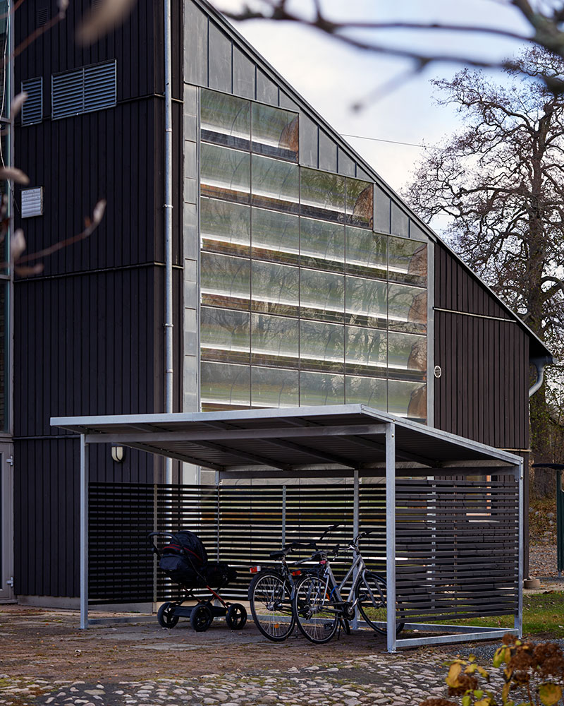 Large bicycle shelter situated outside a large glass office building.